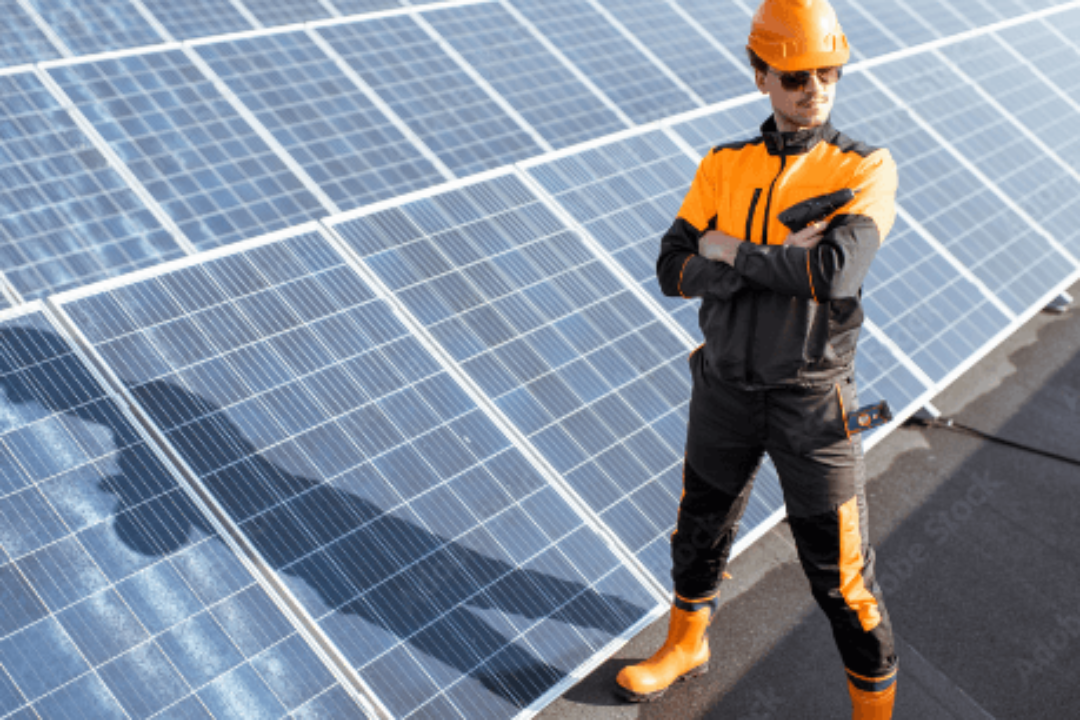 Mitarbeiter steht mit verschränkten Armen vor diversen Solarpanelen