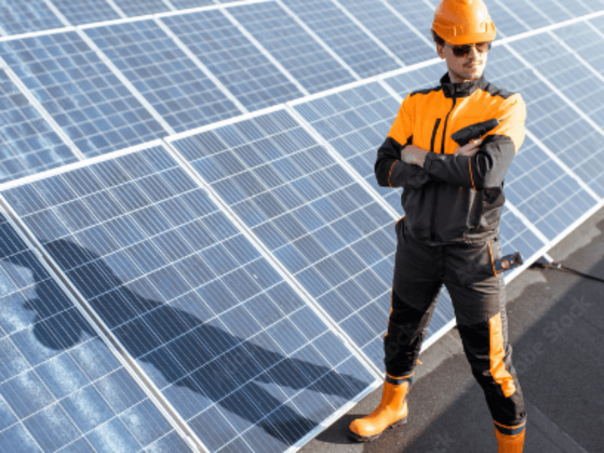 gplusk_content1 Mitarbeiter steht mit verschränkten Armen vor diversen Solarpanelen