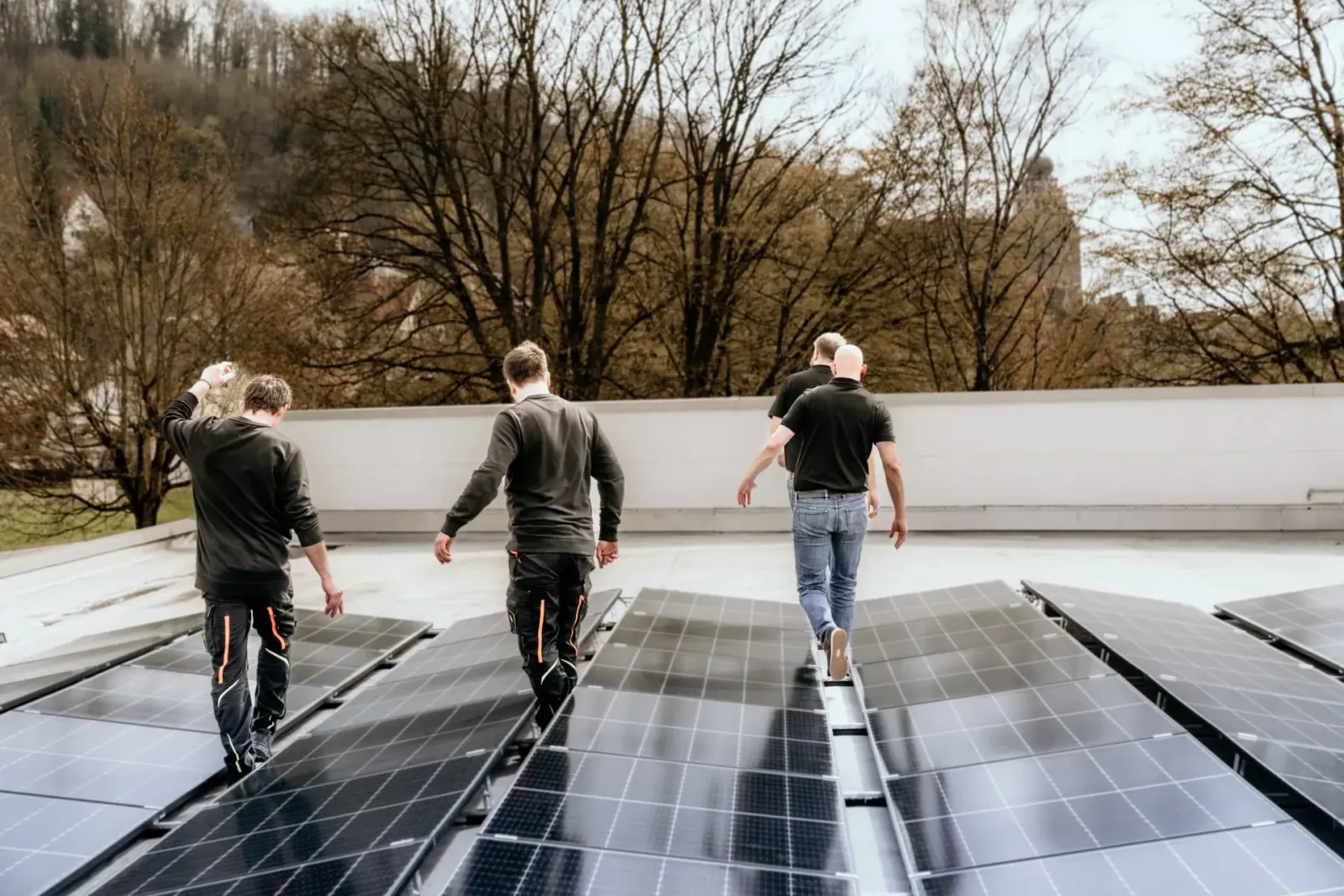 Angestellte von GplusK laufen auf einem Hausdach mit verbauter PV-Anlage
